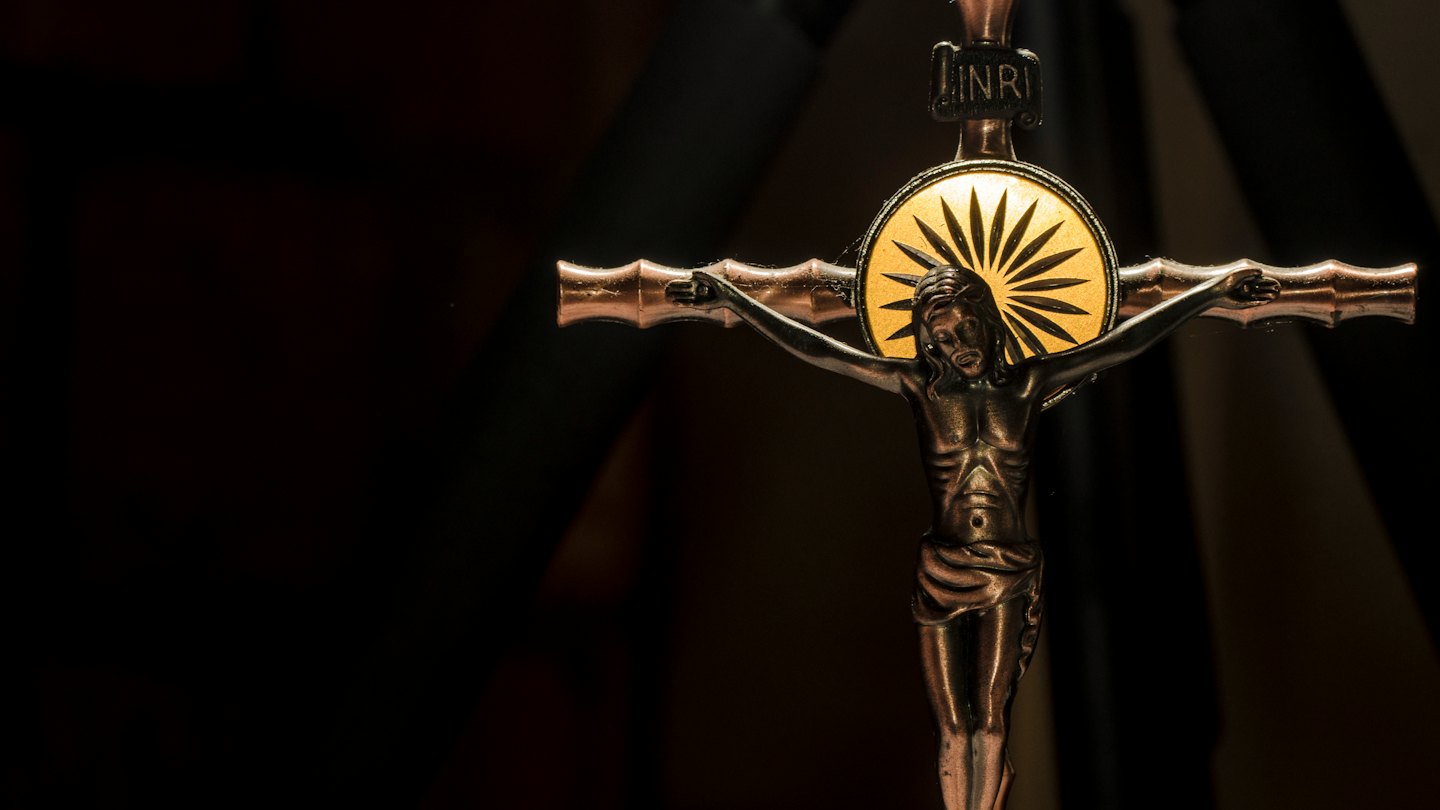 Metallic crucifix of Jesus with a glowing halo.