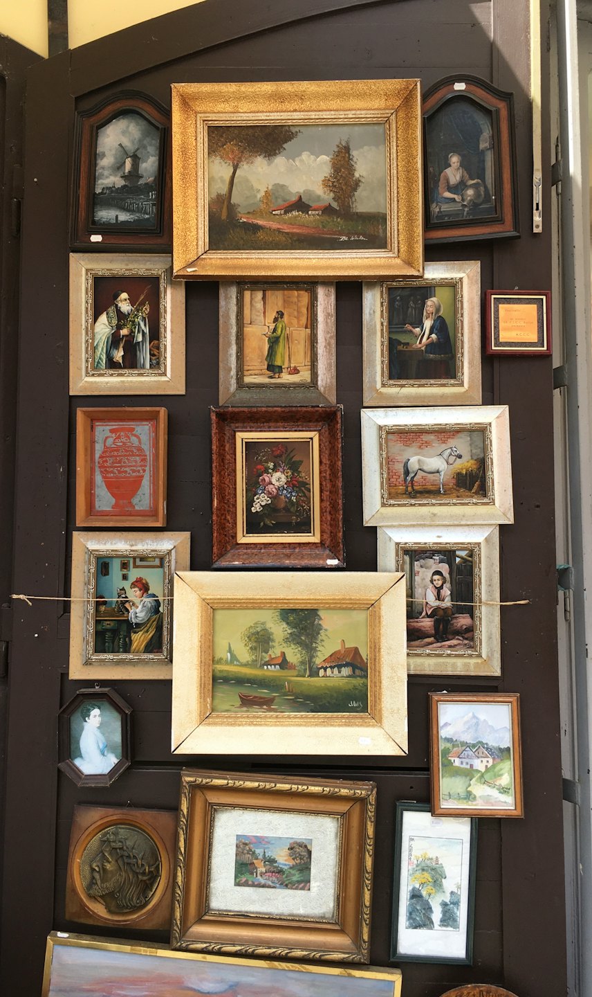 A collection of framed art hangs on a wooden wall.