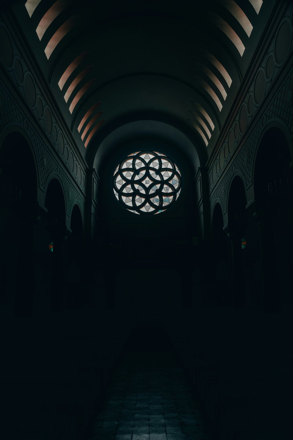 Sunlight shines through a circular stained glass window in a church.
